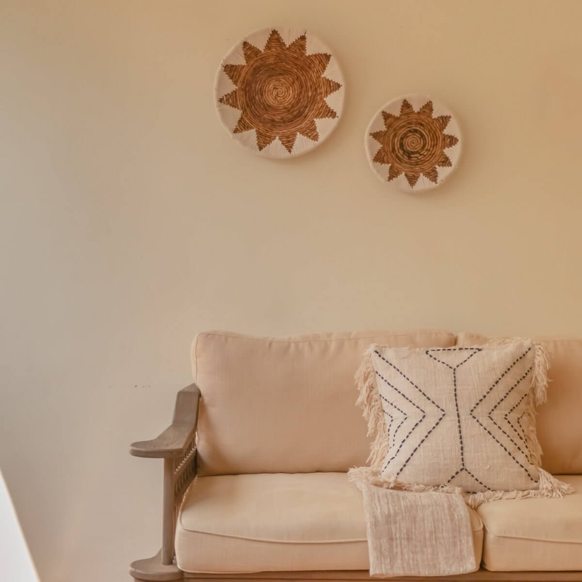 Cozy living room with beige sofa, textured bohemian cushion, and decorative woven wall plates, creating a warm and inviting atmosphere.