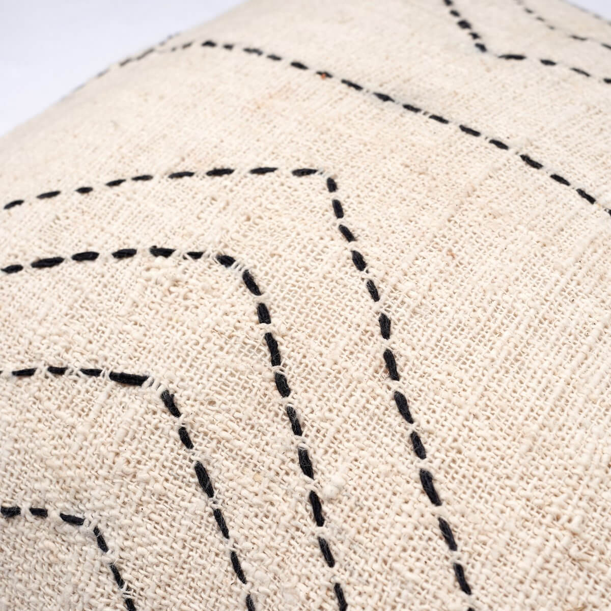 Close-up of a Bohemian style decorative cushion cover, handwoven from natural cotton, featuring black stitched geometric lines.