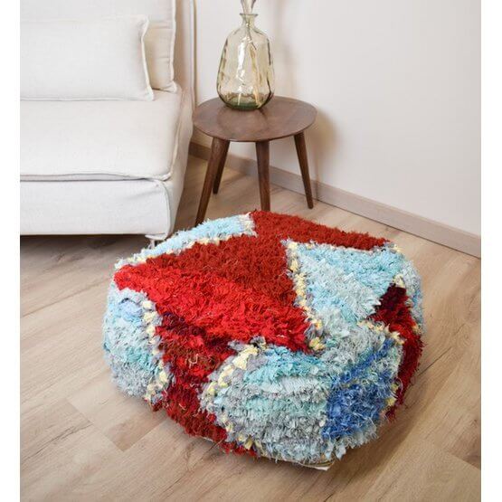 Marokkaans Boucharouite vloerkussen in kleurrijke patronen, handgemaakt van gerecycled textiel, naast een zithoek.