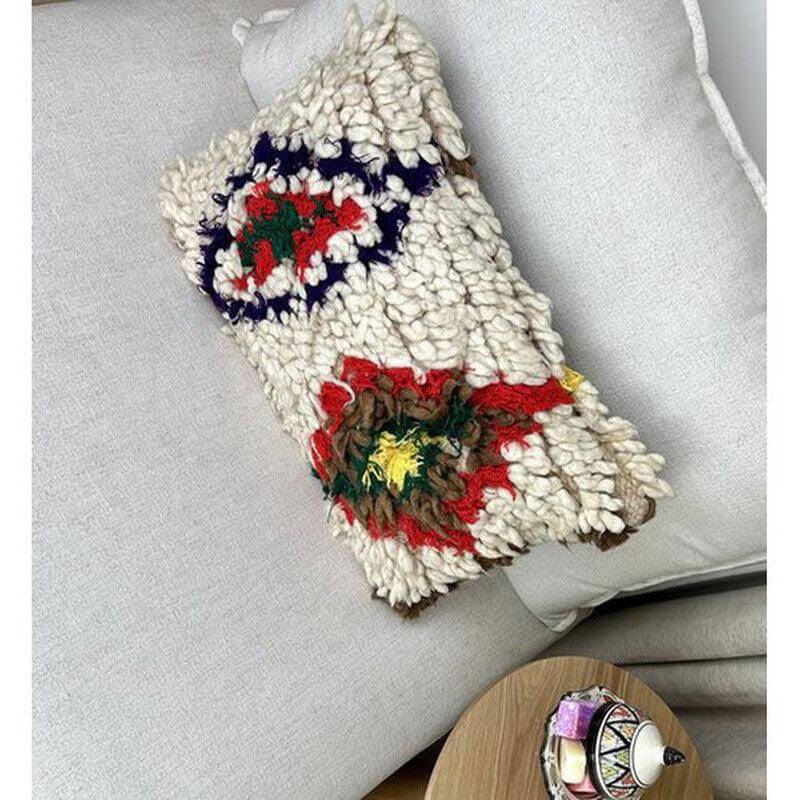 Handgemaakt Marokkaans kussen van vintage Berberkleed, unik kunstwerk op witte bank, creatief en kleurrijk woondecoratie-accessoire.
