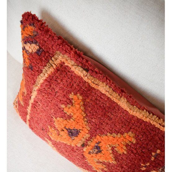 Handgemaakt Marokkaans kussen P711 van vintage Berberkleed in rood en oranje tinten op een lichte achtergrond.