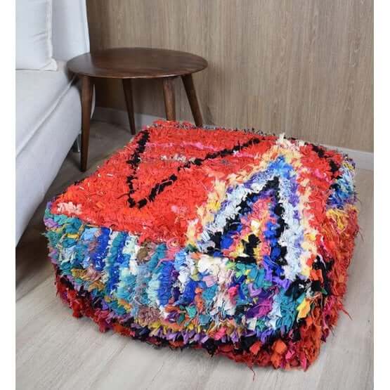 Kleurrijk Marokkaans vloerkussen K1145 in woonkamer, handgemaakt met authentieke patronen en culturele inspiratie, bij een houten tafel.
