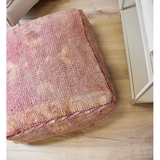 Roze Marokkaans vloerkussen van vintage berberkleed op houten vloer, perfect voor bohemian interieur.
