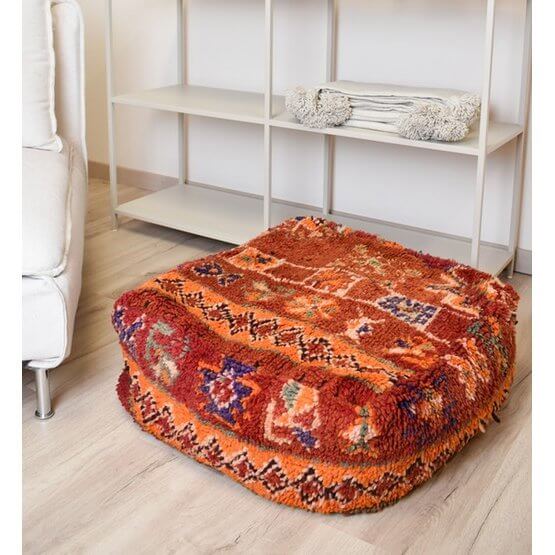 Marokkaans vloerkussen vintage met bohemian stijl, gemaakt van een uniek Berberkleed, in warme tinten in een moderne woonkamer.