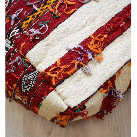 Detail van een uniek, Boheems vloerkussen gemaakt van een vintage Marokkaans berberkleed in rood, oranje en crème tinten.
