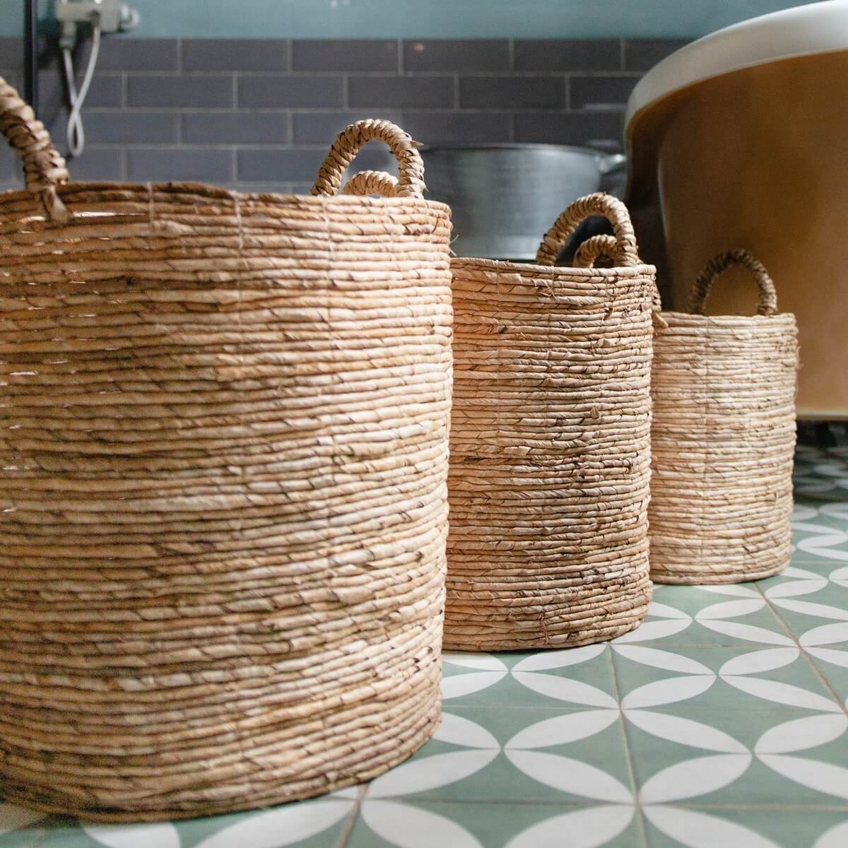 Set van drie opbergmanden SYAILENDRA van duurzame bananenvezel op retro tegelvloer, met handvatten. Ideaal als wasmand.
