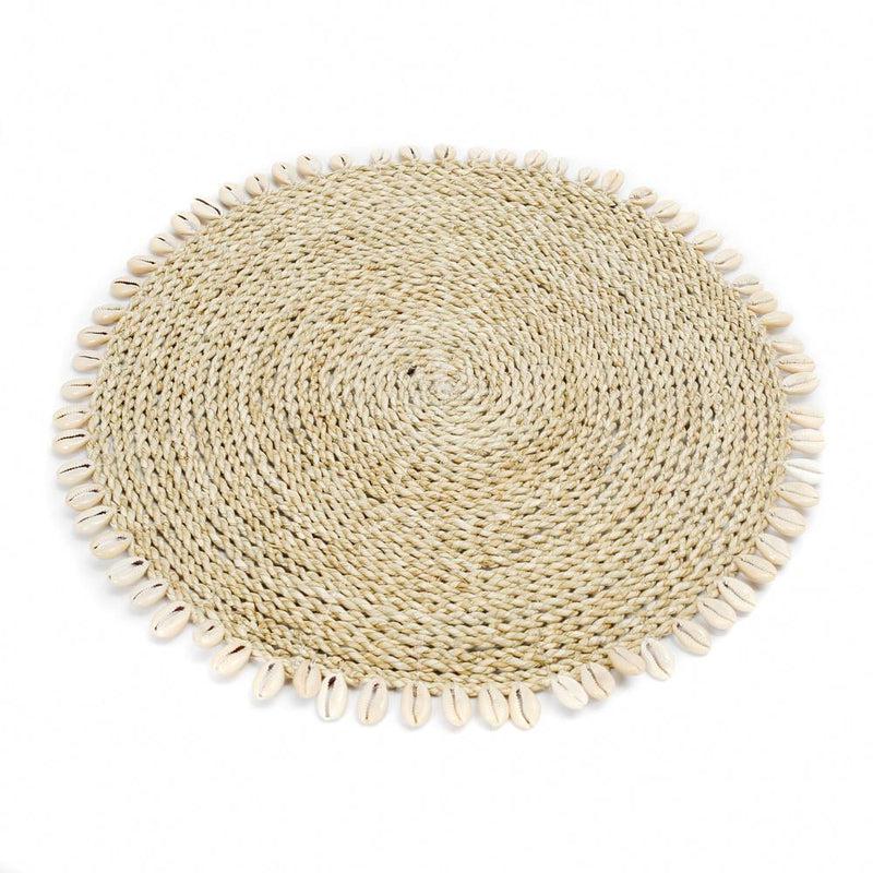 Placemat van zeegras en raffia met kauri schelpen, perfect voor een tropische tafelsetting in boho- of kuststijl.