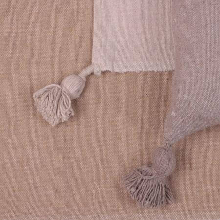 Beige Pompom deken op bank, perfect voor modern of boho interieur, voor een gezellige avond met een kopje muntthee.