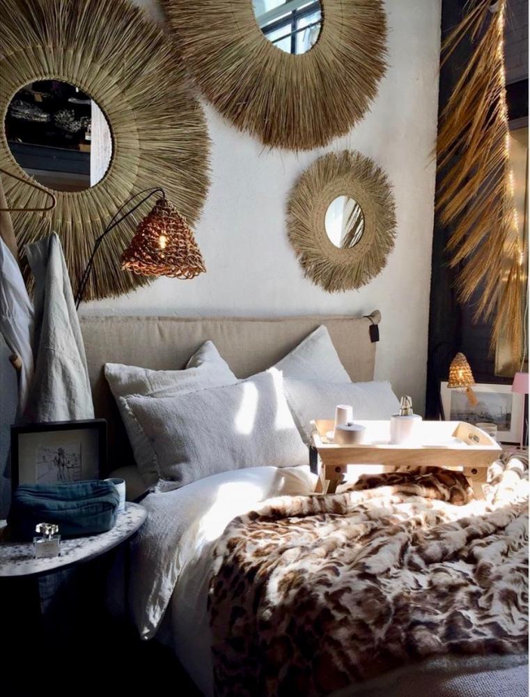 Boho chic slaapkamer met ronde rotan spiegels en natuurlijke decoraties voor een warme, sfeervolle uitstraling.