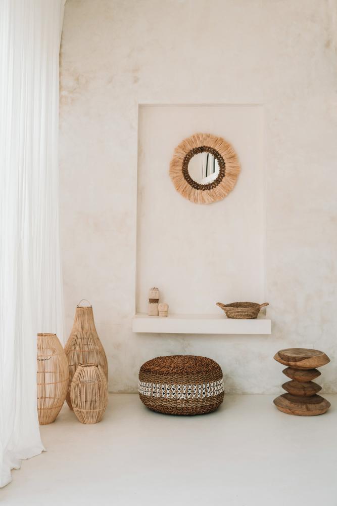 Rustieke woonkamer met rotan potten en een decoratieve spiegel op een witte muur, boho-interieur stijl.