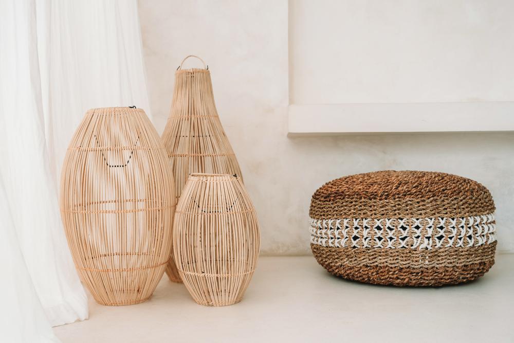 Rotan lantaarns en een geweven poef op lichte vloer in serene ruimte.