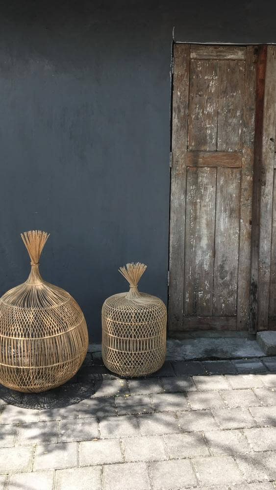 Rotan hanglamp decor, bohemian stijl naast houten deur, sfeervol en warm interieurontwerp.