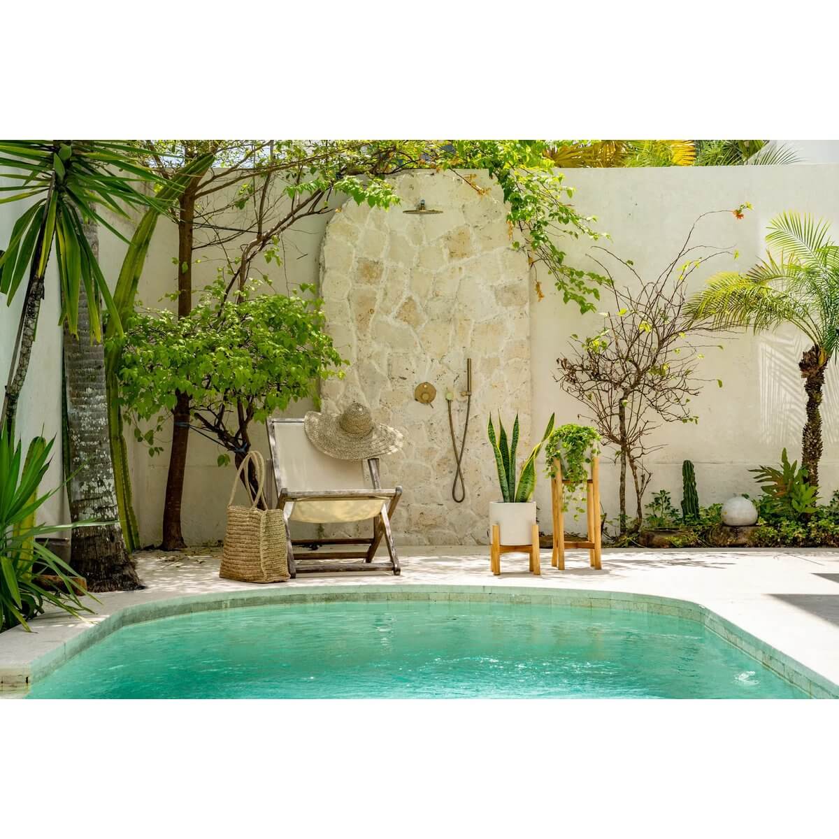 Bohemian poolside patio with chair, lush greenery, and rustic plant holders, evoking a serene tropical oasis vibe.