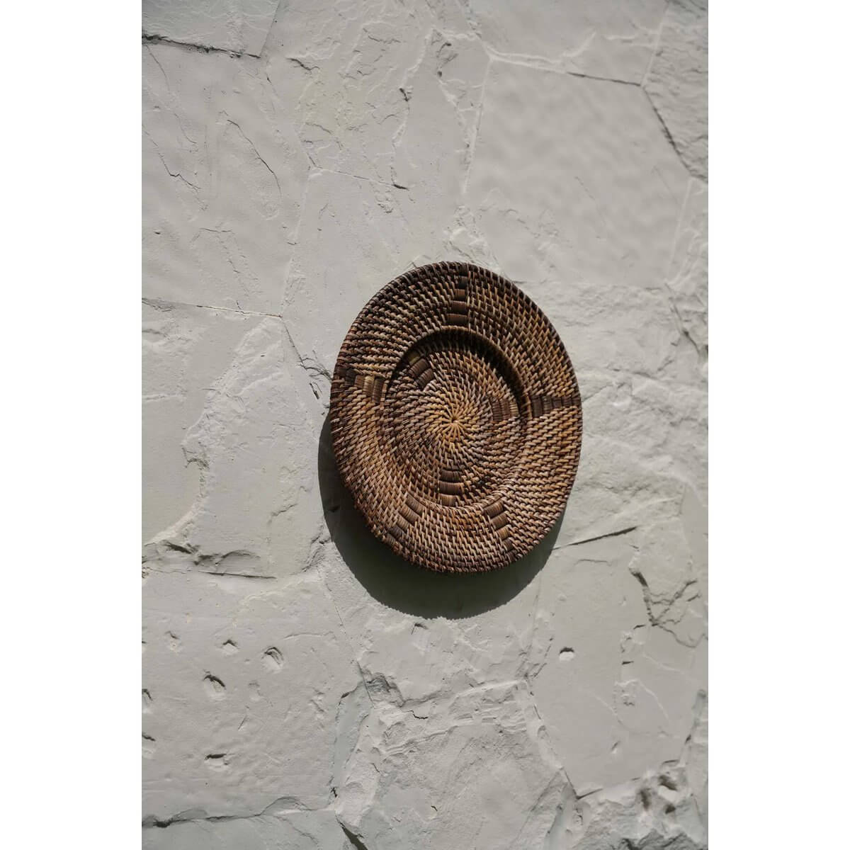 Handgeweven rotan bord met grafische details aan een muur, 40cm breed, natuurlijk etnisch wanddecor in bruine en zwarte tinten.