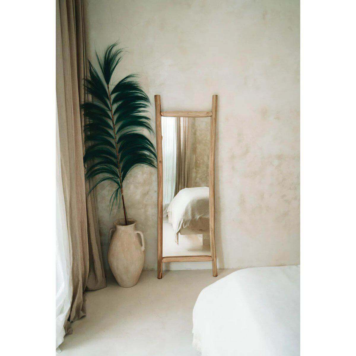 Interieur met handgemaakt bamboetakblad van Bazar Bizar in een vaas naast een spiegel, een stijlvolle decoratie.