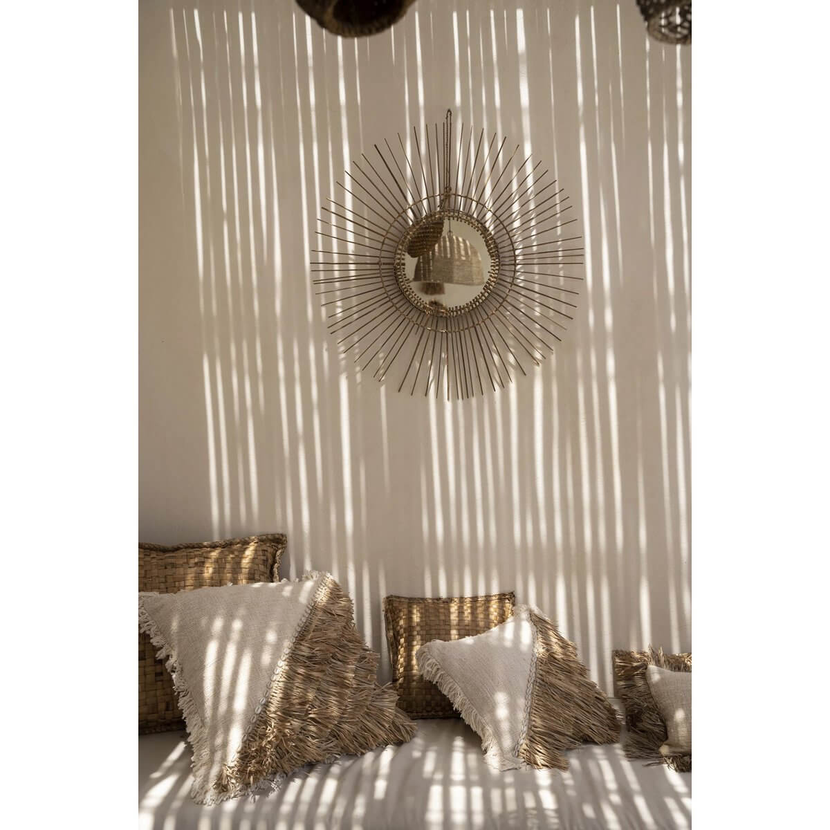 Bohemian Tropical Mirror in natural rattan, casting light patterns on a cozy wall with woven cushions.