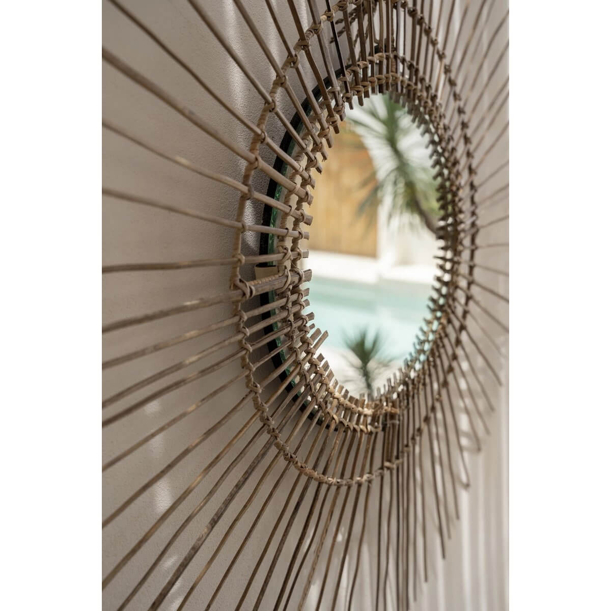 Tropical rattan mirror reflecting a bohemian style with island charm, adding elegance to any room. Perfect for a bold, natural statement.