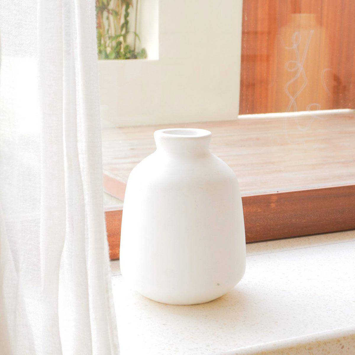 Witgekleurde handgemaakte Bawa vaas van natuurlijke klei, ronde vorm, 15 cm doorsnede, op vensterbank voor een boho-accent.