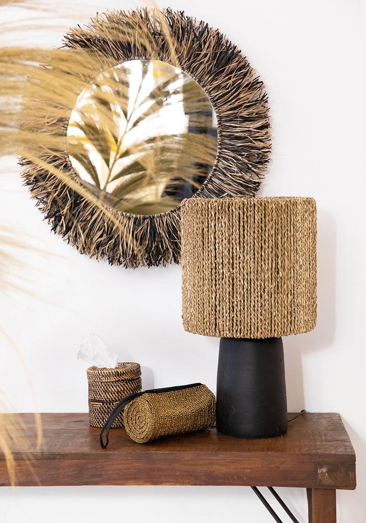 Handgeweven rotan lamp en tissuehouder op houten tafel, met decoratieve spiegel, natuurlijk interieur design