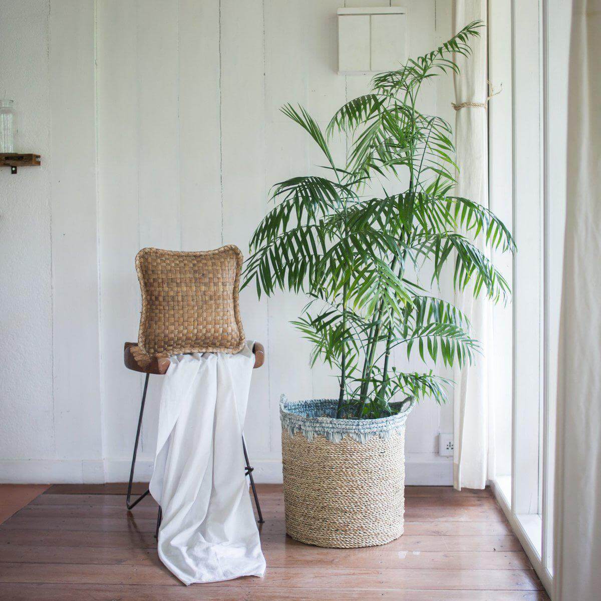 Grote zeegras opbergmand met plant, rustieke stoel en witte decoratie in lichte kamer