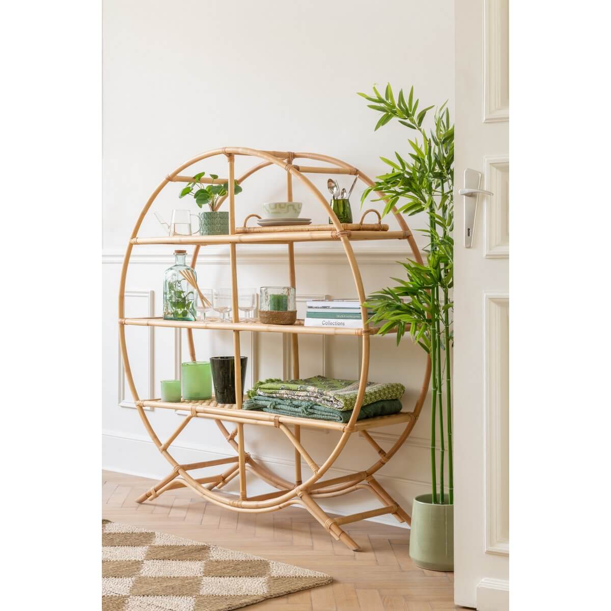 Ronde bamboe kast met groene decoraties en een plant in een modern ingerichte kamer.