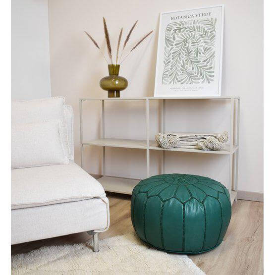 Groene leren poef in een gezellige woonkamer met boho sfeer, ideaal als voetenbank of extra zitplek, naast beige bank.