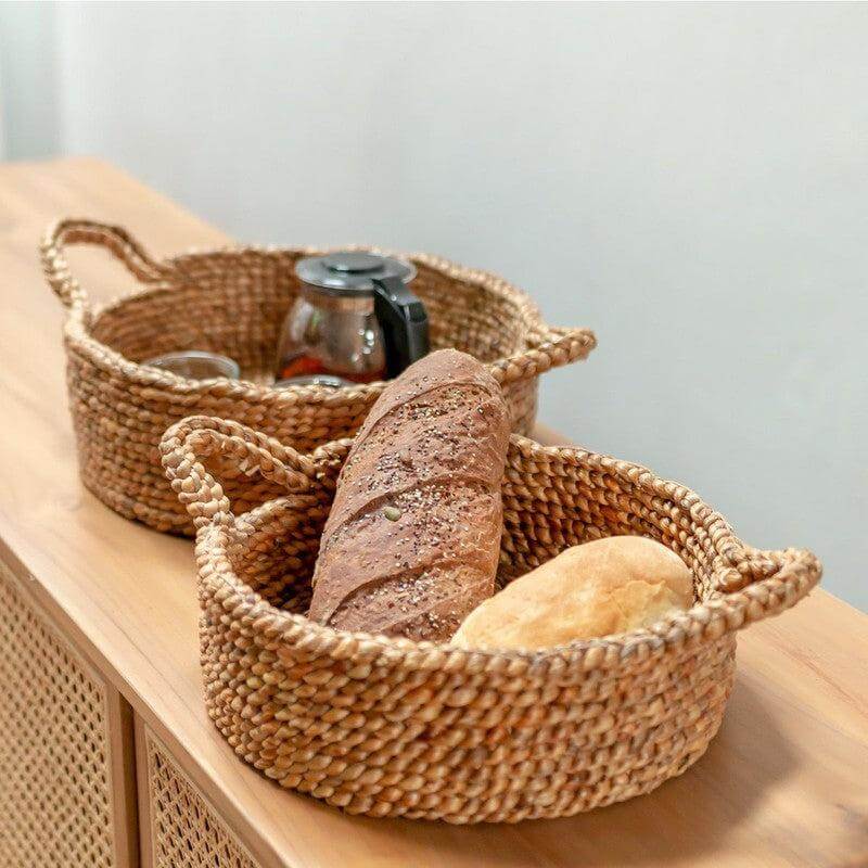 Twee ronde opbergmanden van waterhyacint op tafel met brood, ideaal als broodmand of fruitschaal, handgemaakt en duurzaam.