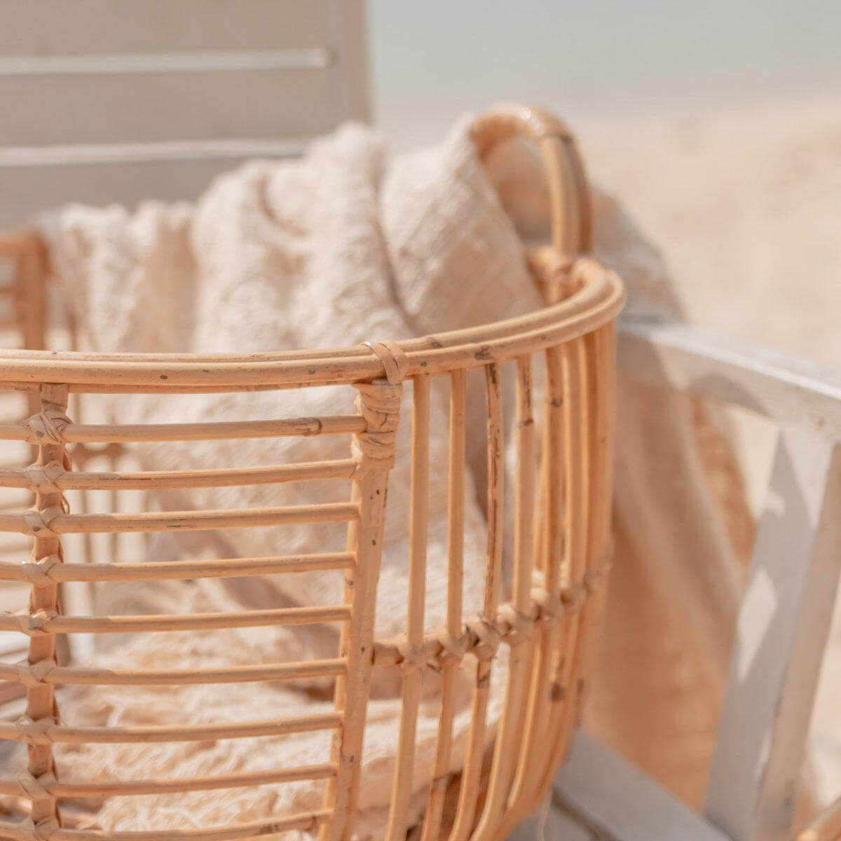 Rotan opbergmand JEMUH met handvatten, ideaal voor was en opbergen, gemaakt van duurzaam materiaal, strandachtergrond.