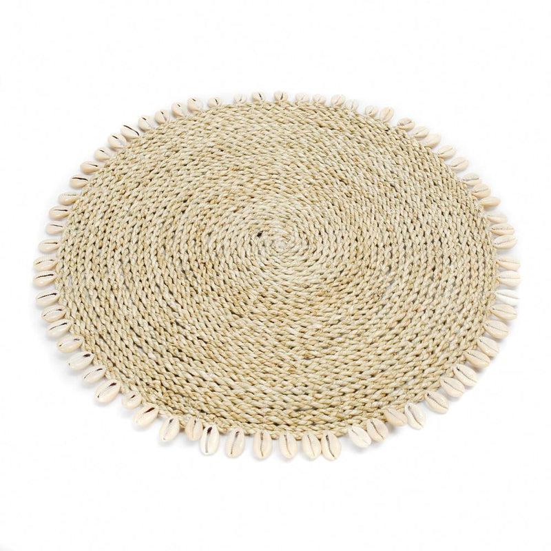 Placemat van zeegras en raffia met kauri schelpen, perfect voor een tropische tafelsetting in boho- of kuststijl.