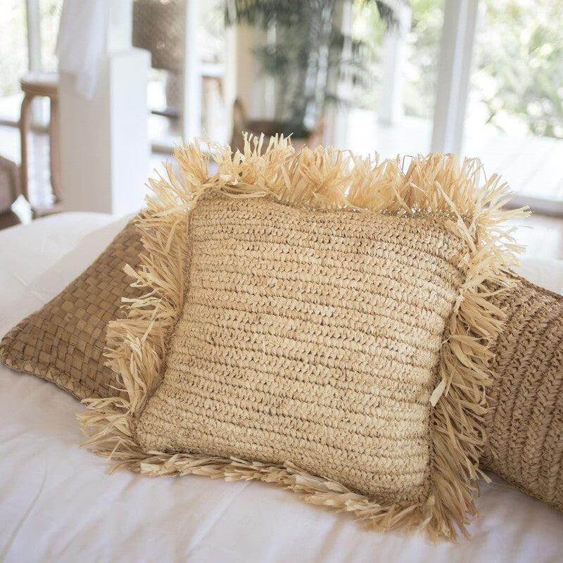 Naturel raffia sierkussen GANDI op een bank, handgemaakt en duurzaam, perfect als decoratieve eyecatcher voor een gezellige sfeer.