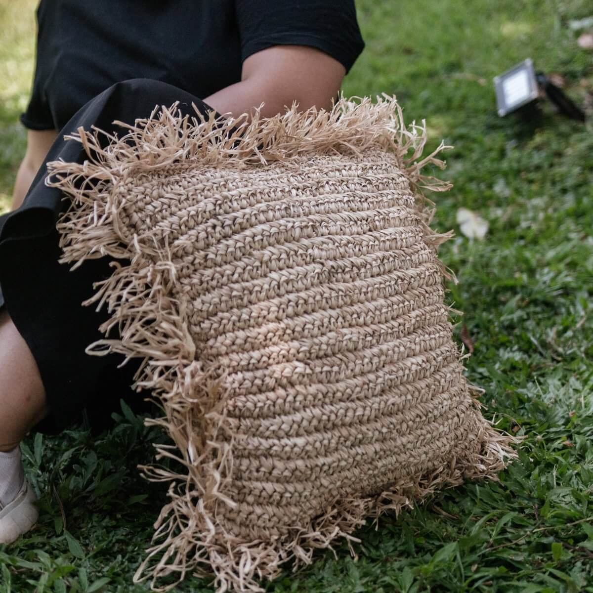 Decoratief Sierkussen GANDI van raffia, op gras geplaatst, met handgemaakte textuur en natuurlijke uitstraling, ideaal voor sofa of bed.