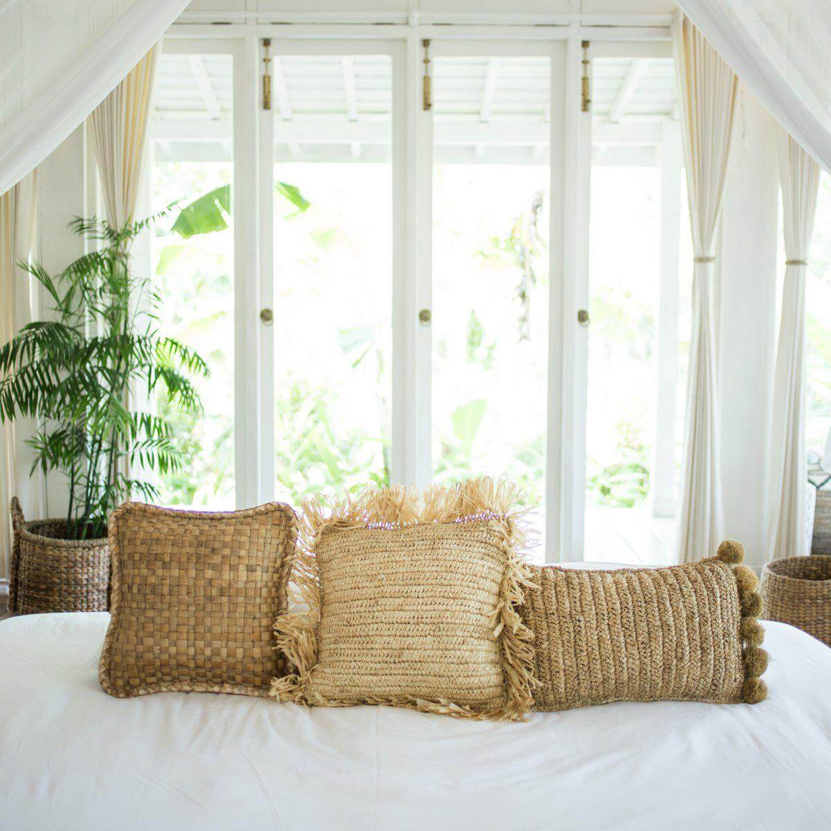 Sierkussens van raffia op een bed, natuurlijke textuur en handgemaakt design, perfect als decoratieve blikvangers in huis.